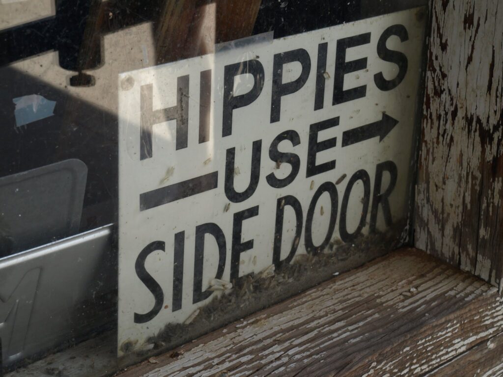 Skilt: Hippies use side door. 

Hackberry General Store, Route 66, Arizona, USA. Bikere måtte godt bruge hovedindgangen.